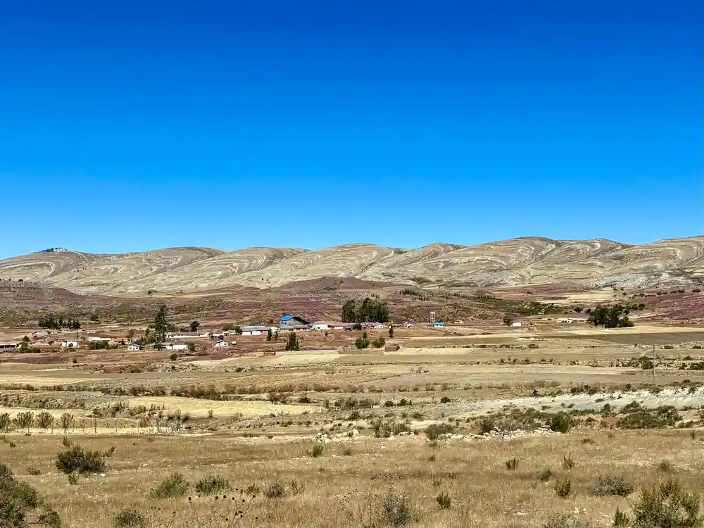 Fields and scattered buildings on the crater floor under a deep blue sky