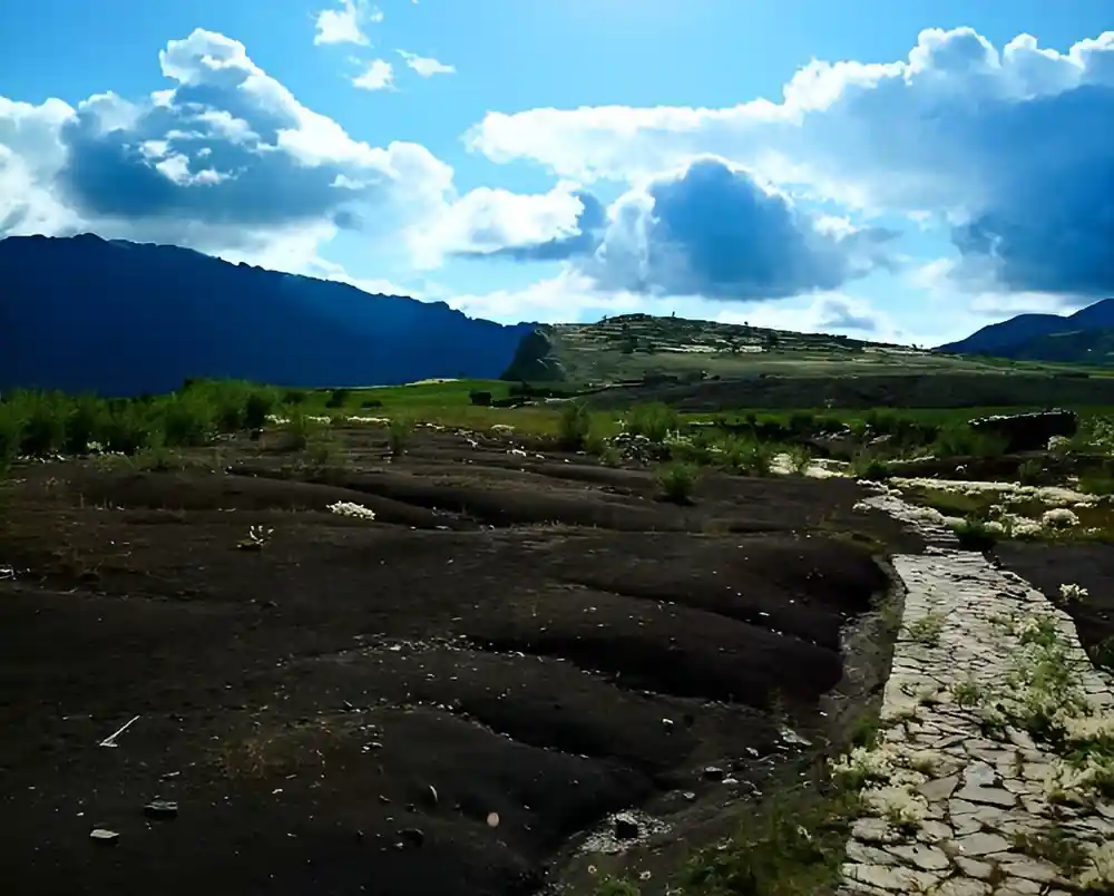 Green terraces and dark rock in the valley below the crater rim