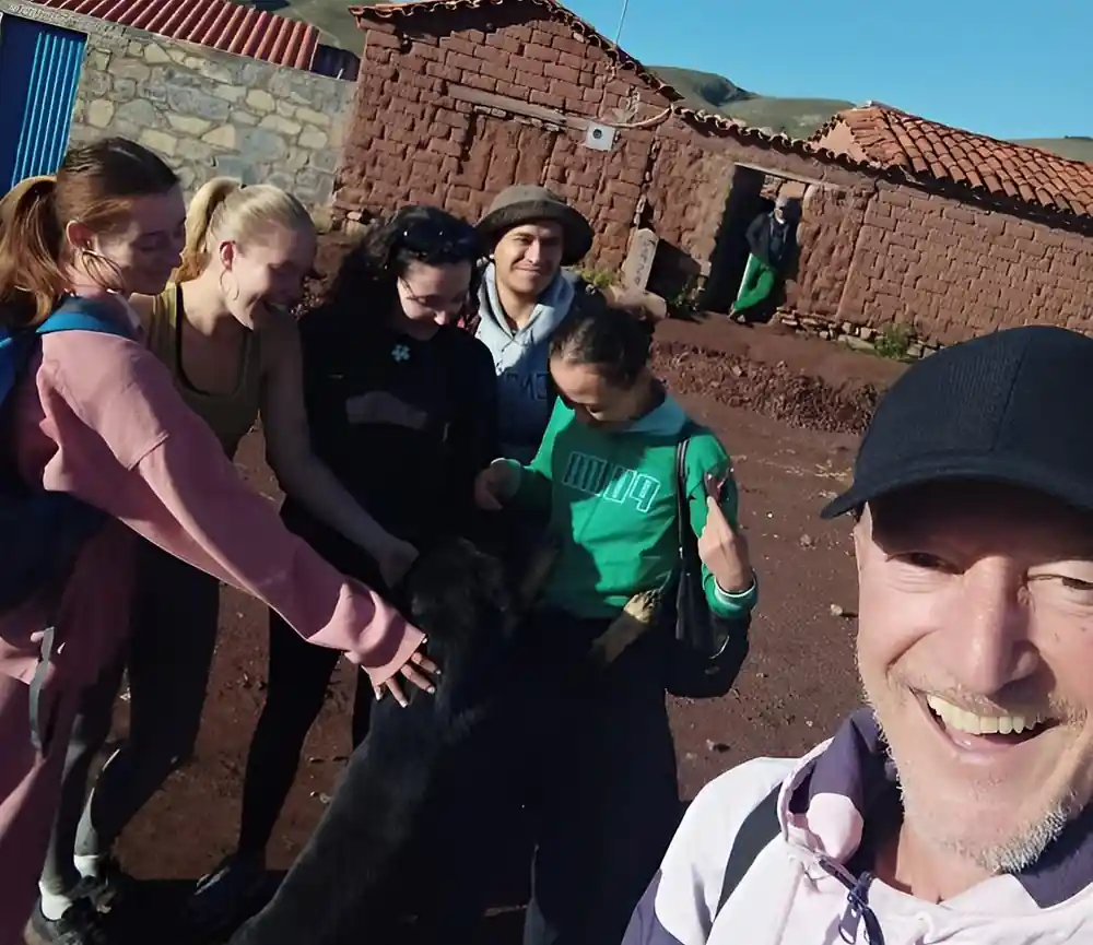 A group of visitors and a local family beside an adobe house