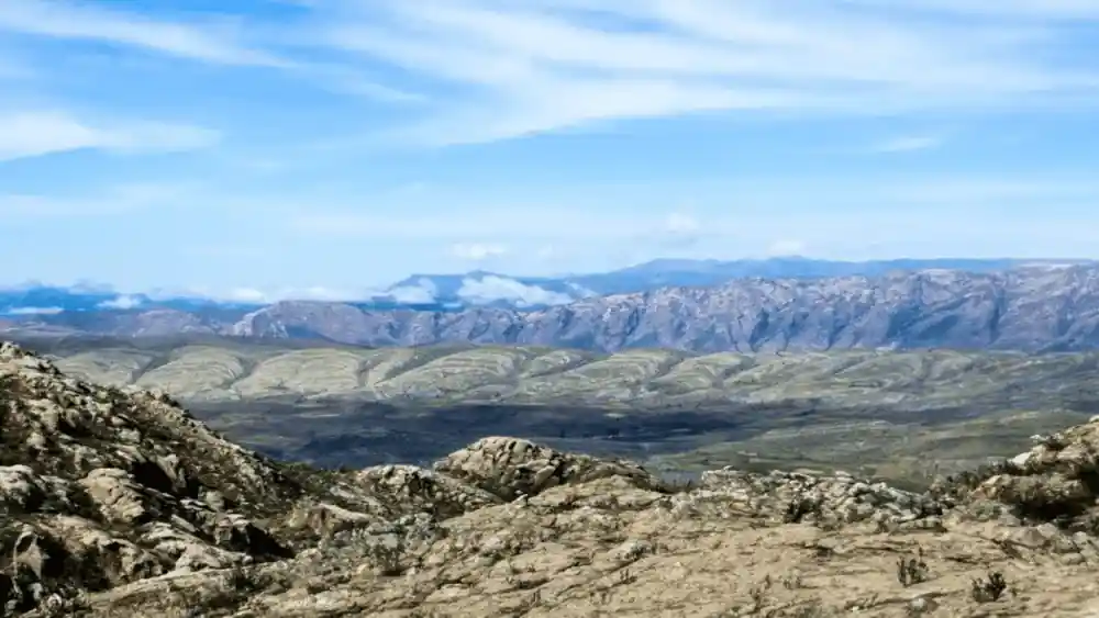 Layered ridges receding to a distant range from a rocky foreground