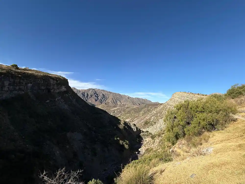 A narrow gorge cut deep into pale rock with hills beyond