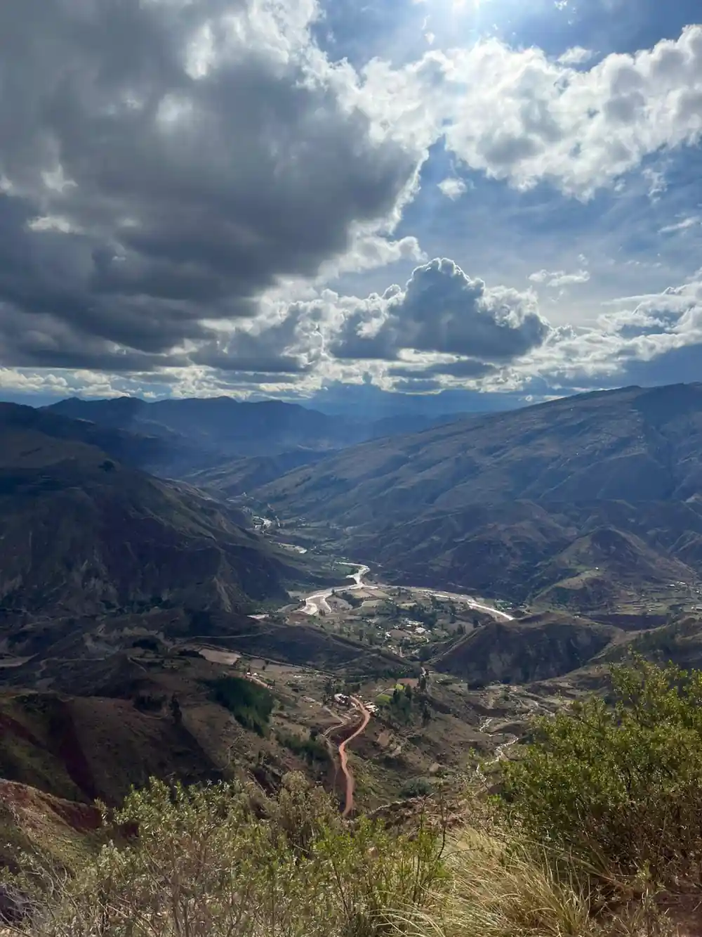 A river valley far below, seen from a high viewpoint under cloud
