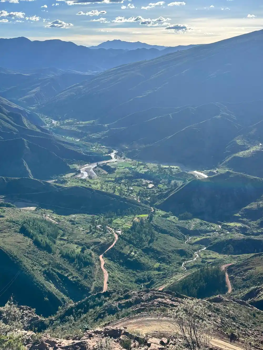 A road winding along a green valley floor seen from far above