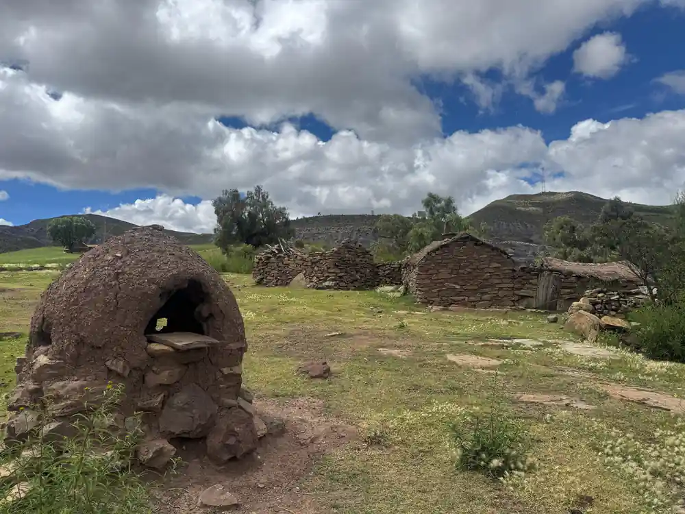 A stone oven and adobe buildings under a cloudy sky