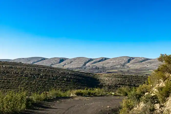 Tilted rock beds running across a wide valley floor under a clear sky